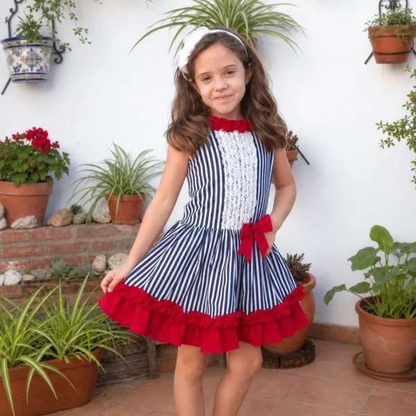 Niña con vestido marinero de rayas azul marino, encaje blanco y volantes rojos
