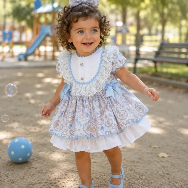 Niña con vestido estampado celeste Romina jugando en el parque con pelota azul