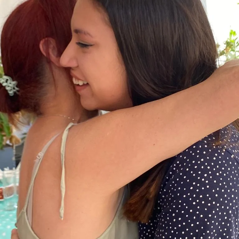 Dos mujeres abrazándose con una sonrisa en un momento cercano y emocional
