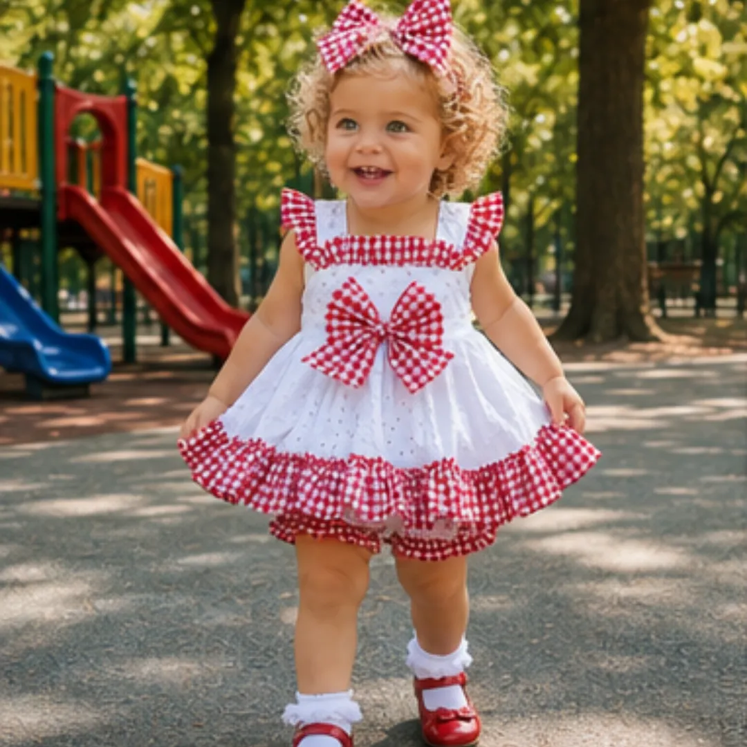 Niña caminando en parque con vestido corto blanco y volantes de cuadro vichy rojo